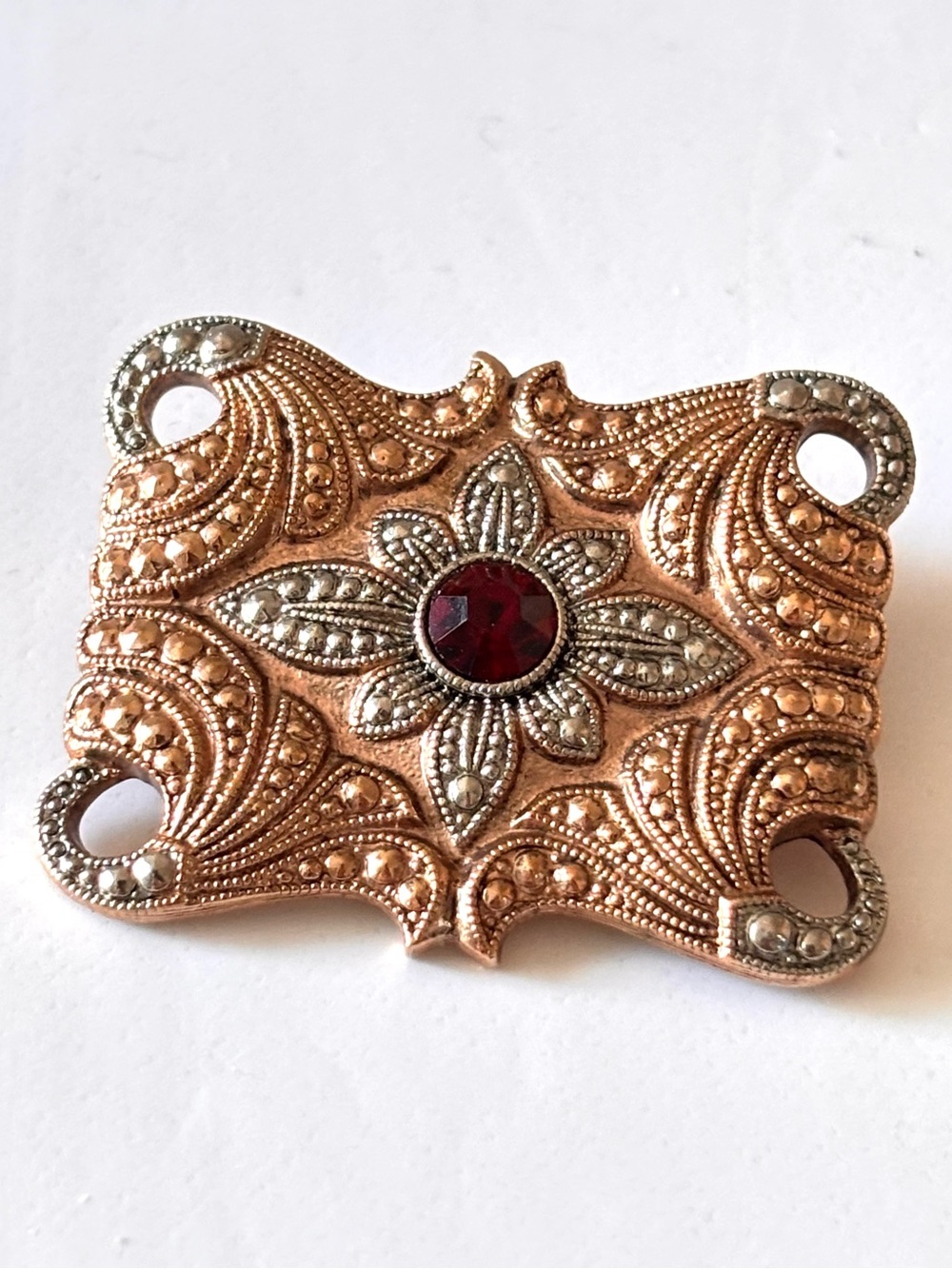 Rose gold and silver toned with a ruby colored stone brooch